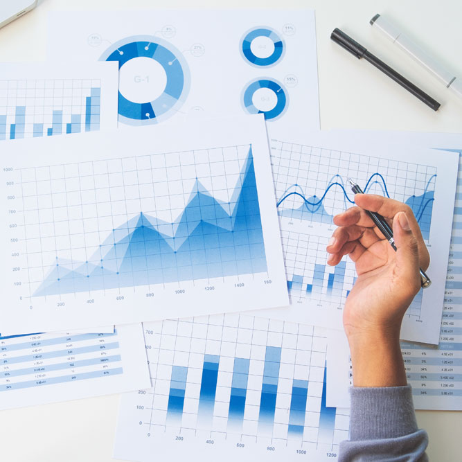 يد تحمل قلمًا فوق التقارير